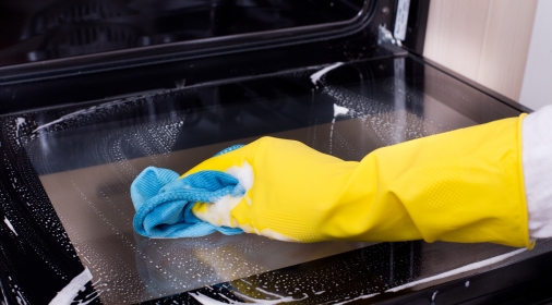 Woman cleaning oven with yellow glove