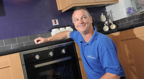 Ovenclean specialist kneeling in front of oven