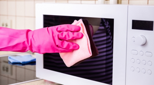 manual microwave cleaning with pink rubber glove