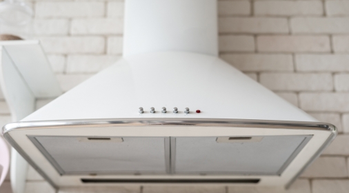 Modern cooking exhaust hood against brick wall. Element of contemporary kitchen at home with white interior