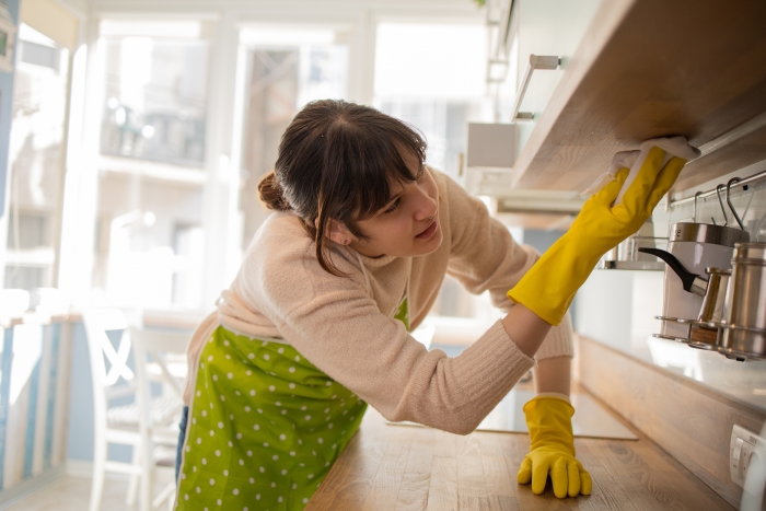 Young woman cleaning under the kitchen cupboards
